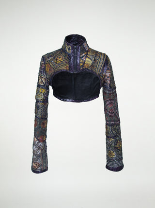 The front view of an over-bust shrug that is encrusted with gold embroidery, mirrors, and silver threads.