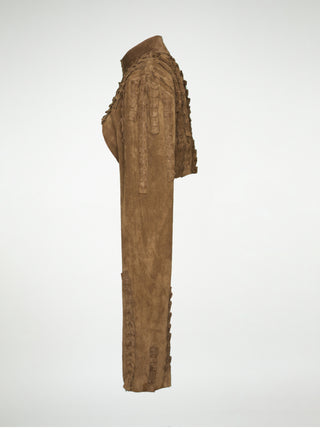 A side view of a brown suede over-bust shrug jacket with long sleeves and strips of pleated leather stitched onto the shoulders and sleeves.