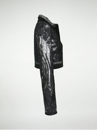 A side view of a black and silver distressed cotton waist-length jacket with overlays of sequins, black lace, metallic embossed leather, and black leather.
