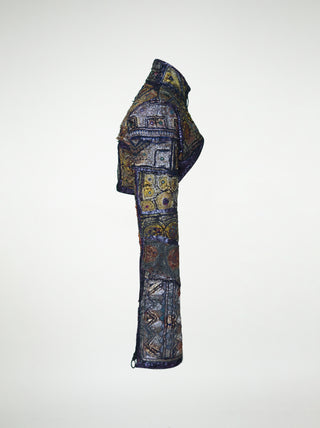 The side view of an over-bust shrug that is encrusted with gold embroidery, mirrors, and silver threads.