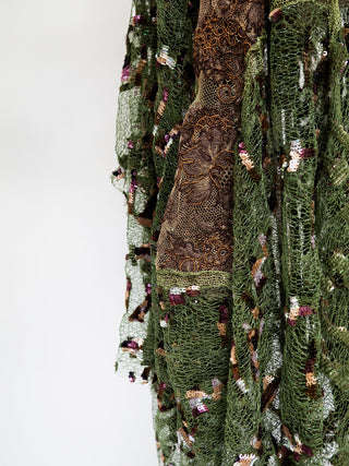 A close up of green and brown lace with small multi-coloured sequin details