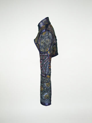 The side view of an over-bust shrug that is encrusted with gold embroidery, mirrors, and silver threads.