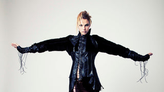 Woman wearing a dark, edgy jacket with tight shearling sleeves and a corseted, laced up bodice.
