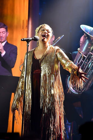 MEASHA BRUEGGERGOSMAN wearing a call and response gown and fringed jacket while performing.