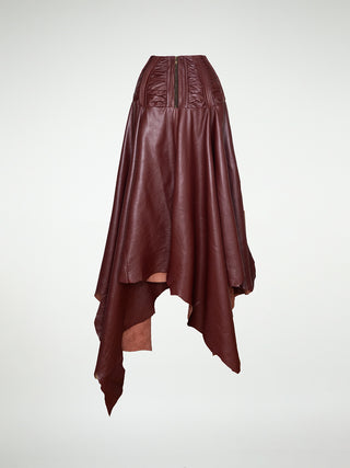 A back view of a maxi-skirt with an asymmetrical hemline, made of oxblood leather, featuring a metal zipper closure at the back.