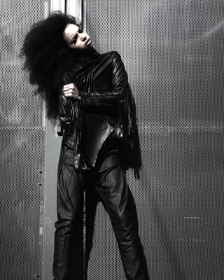 Person wearing a black outfit with a textured wall background