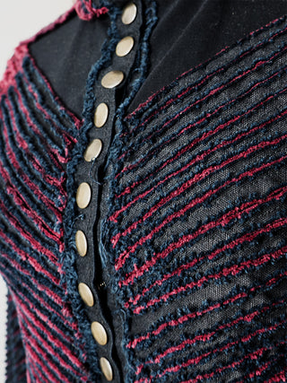 A closeup of a  fitted black jacket with a chevron pattern, featuring a collar, button details, and a front snap closure.