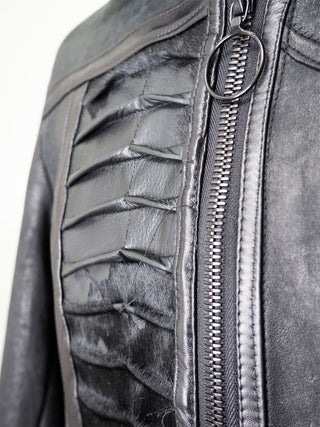 A closeup of a black leather men's jacket with a panel of pleated cowhide on the front and back.