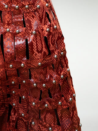 Closeup of wide leg leather trousers with woven leather panels and stud embellishments.