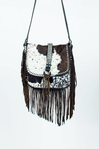 Cowhide leather handbag with fringe and studs on a white background