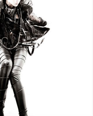 Person wearing a dark outfit with leather elements on a white background