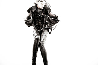 Person wearing a dark outfit with leather elements on a white background