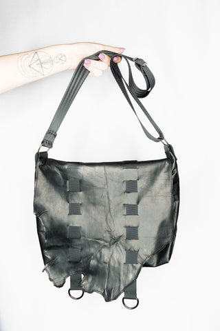 Black bag with straps held by a hand on a white background
