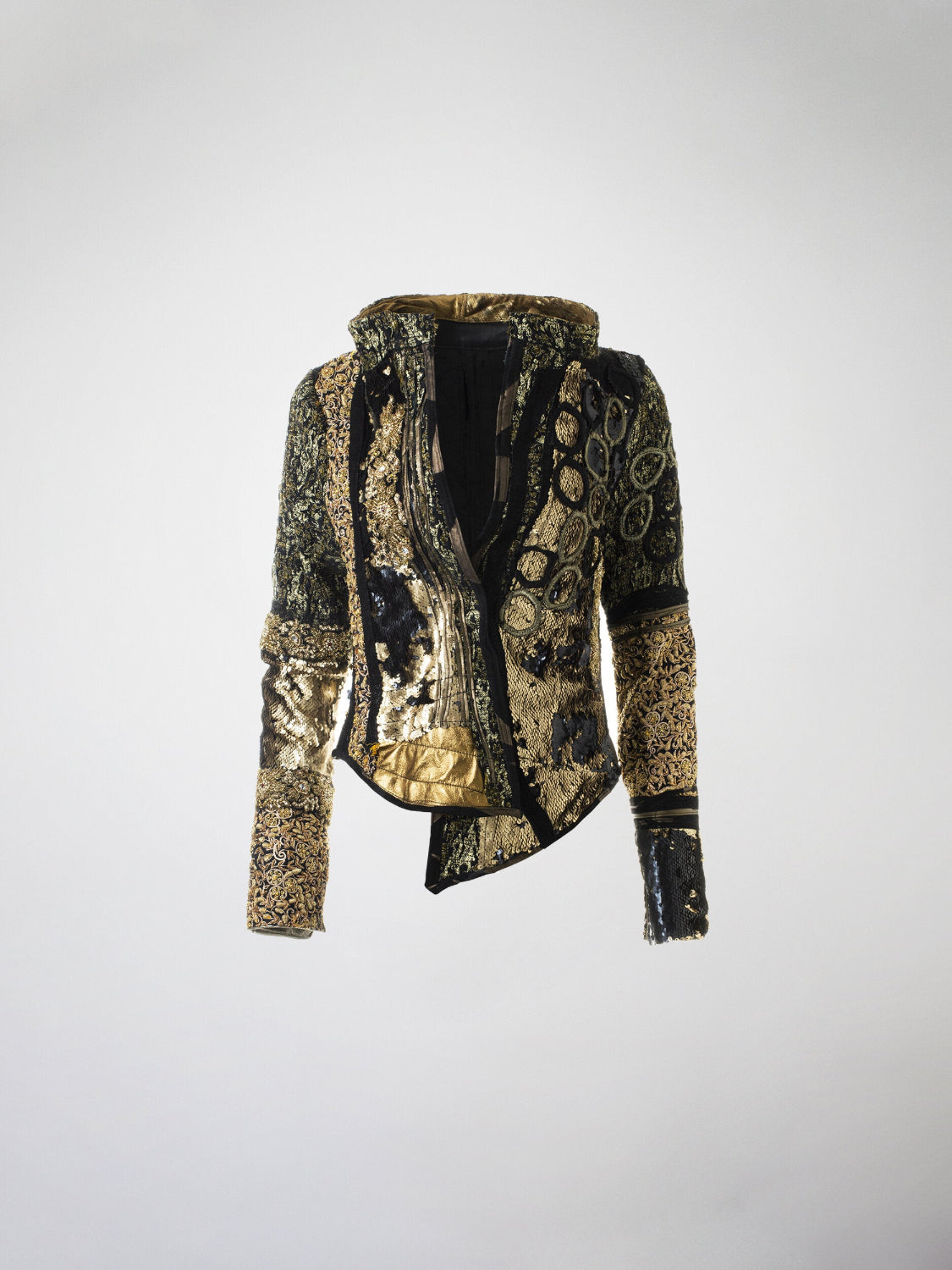 A gold and black mosaic jacket featuring silk brocade, metallic leather, sequins, beaded silk trim, lace, and Swarovski crystal embellishments, with a metal zipper closure.