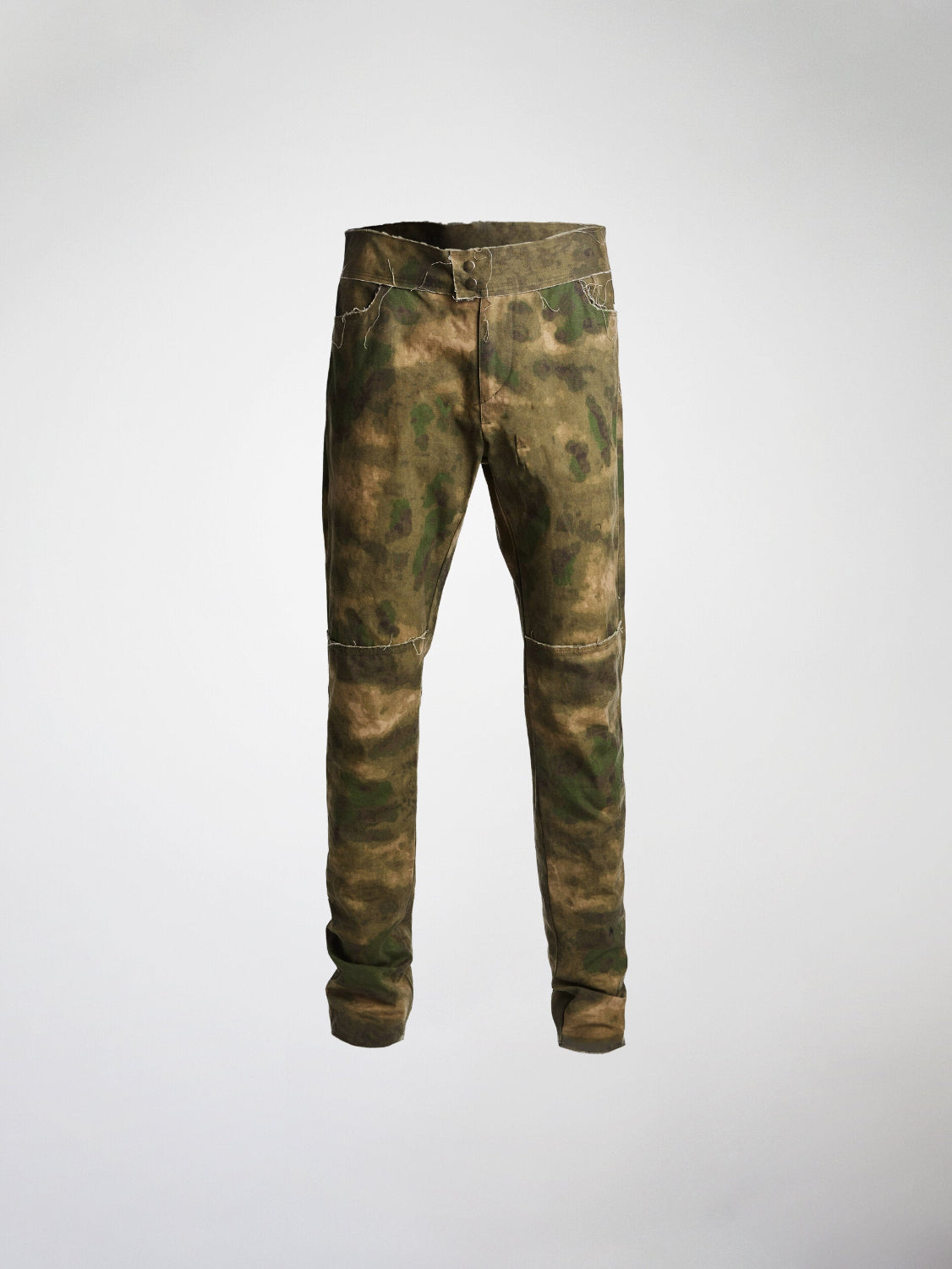 A pair of camouflage print waxed cotton trousers with unfinished-look seams and hems, featuring a metal zipper and metal snap closure.