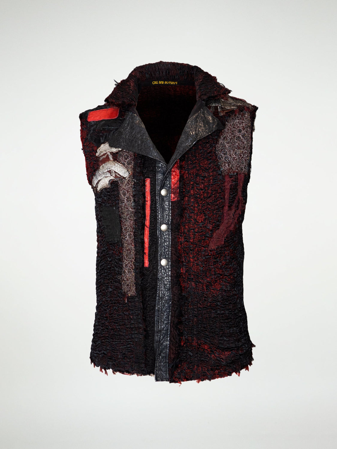 A black and red textured vest with red leather patches, embroidered appliqué, and button-up front.